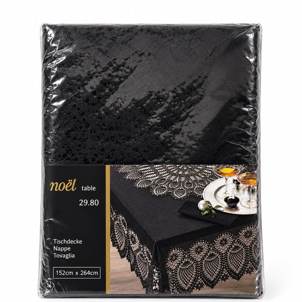 A black tablecloth with an intricate lace-like floral border, shown in its clear plastic retail packaging with a printed label. The label features the brand name 'noël' and displays a lifestyle image of the tablecloth styled on a table with glasses and a napkin.