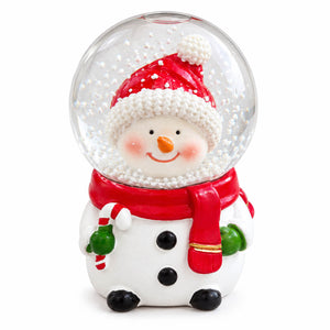 A festive snowman snow globe figurine with a red Santa hat, red scarf, green mittens, and black buttons on a white background.