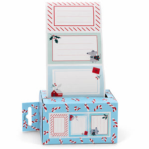 A Christmas-themed paper mailer box with a hanger hole on the side, featuring a light blue base printed with candy canes, a gray mouse, a small red house, and holiday motifs. A matching flap card is shown standing open above the box, with lined writing areas and holiday illustrations.