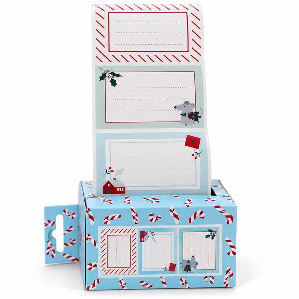 A Christmas-themed paper mailer box with a hanger hole on the side, featuring a light blue base printed with candy canes, a gray mouse, a small red house, and holiday motifs. A matching flap card is shown standing open above the box, with lined writing areas and holiday illustrations.
