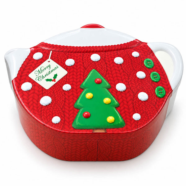 A Christmas-themed teapot or tea pot with a red knitted sweater design, green Christmas tree, white handle, and a hanging 'Merry Christmas' tag, shown on a white background.