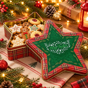 A festive Christmas star-shaped metal cookie tin shown open with assorted decorated cookies inside, alongside the matching lid. The lid is green with white 'Merry Christmas' script and gold holiday details, and the tin has a red plaid border.