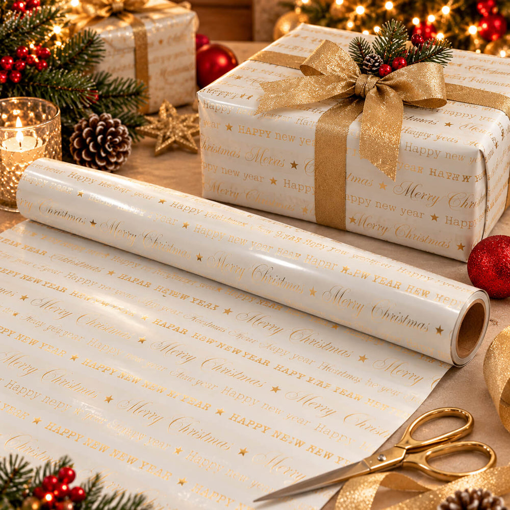 Gold and white Christmas wrapping paper with 'Merry Christmas' and 'Happy New Year' text, shown both rolled out and wrapped around gift boxes with a gold ribbon and bow, surrounded by holiday decorations.