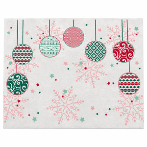A square white fabric placemat or napkin featuring a festive Christmas pattern with hanging ornaments, snowflakes, and stars in red, green, and pink.