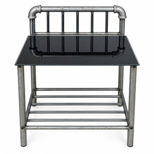 Industrial-style end table featuring a black glass top and a weathered silver metal frame with pipe details on the backrest and lower shelf, shown against a plain white background.