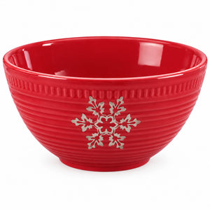 A red ceramic bowl with a ribbed exterior, featuring a silver snowflake and holly leaf design on the front, set against a plain white background.