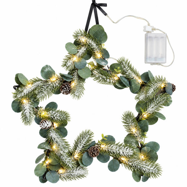 A star-shaped Christmas wreath with green pine branches, eucalyptus leaves, faux snow, small pinecones, and warm white string lights, hanging from a black ribbon with a battery pack visible at the top right.