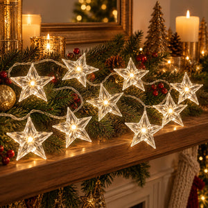 Star-shaped clear glass string lights glowing warmly on a decorated Christmas mantel with green garland, candles, ornaments, and pinecones.