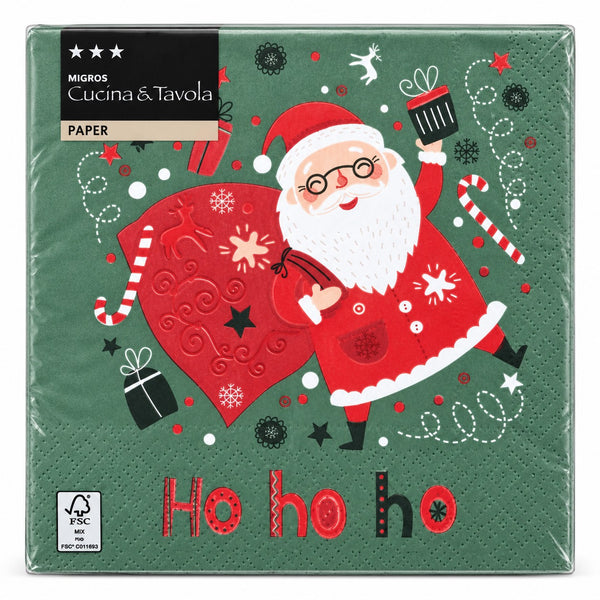 A pack of square paper napkins from Migros Cucina & Tavola, featuring a festive Christmas design with Santa Claus, a large red sack, candy canes, and 'Ho ho ho' printed on a dark green background.