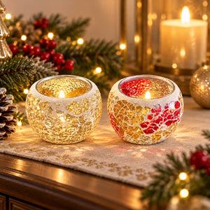 Two small mosaic tealight candle holders on a table runner in a cozy holiday setting. One holder is white with gold crackle mosaic and a lit tealight, and the other is white with red and gold mosaic and a lit tealight.