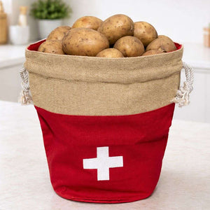 Red bucket with a white cross and jute liner filled with potatoes on a light background