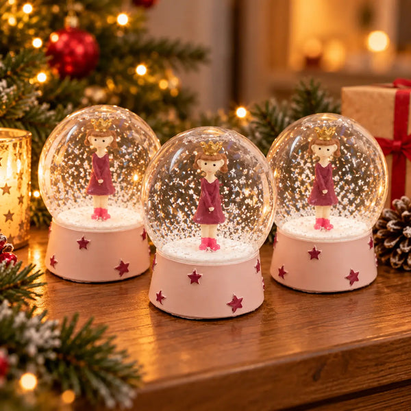Three Migros Christmas girl snow globes displayed together in festive décor