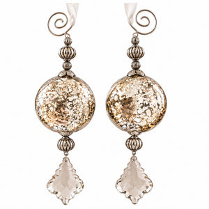 A pair of dangling statement earrings with large textured gold-toned round beads, silver-toned filigree details, spiral ear hooks, and clear faceted clover-shaped drops, shown on a plain white background.