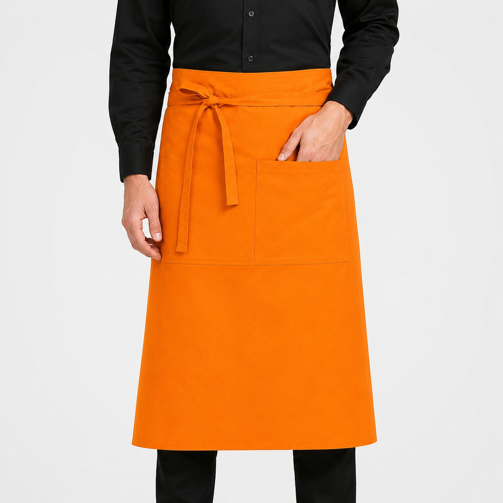 Professional chef wearing a bright orange Jobeline Taglio waist apron while preparing vegetables in a commercial kitchen.
