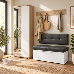A modern entryway scene showing a white and dark gray storage bench with a tufted backrest, next to a tall mirrored wardrobe. A wooden coat rack on the wall holds a beige coat, a woven bag, and a scarf.