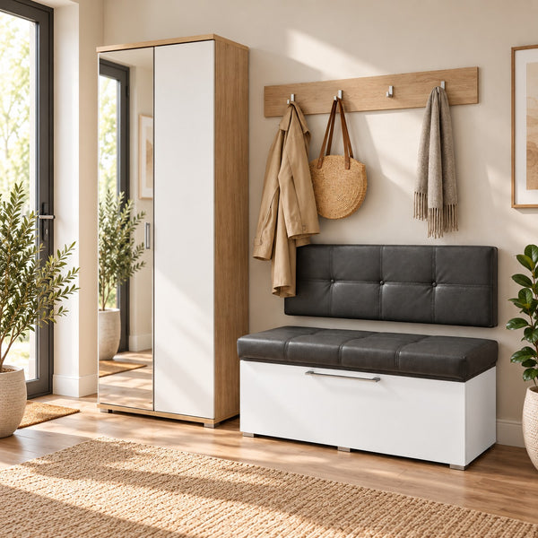 A modern entryway scene showing a white and dark gray storage bench with a tufted backrest, next to a tall mirrored wardrobe. A wooden coat rack on the wall holds a beige coat, a woven bag, and a scarf.