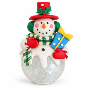 A festive Christmas snowman figurine with a red top hat, green holly accents, a green and white plaid scarf, red mittens, candy canes, and a blue gift box with a yellow bow, set against a plain white background.
