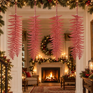Four pink glittery pine branch hanging ornaments suspended in a decorated holiday living room with a fireplace, garlands, and warm lights.
