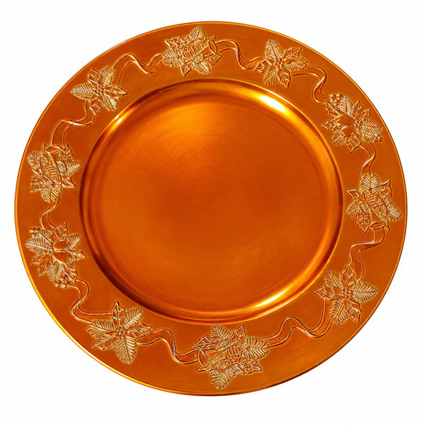 An orange metallic charger plate with a raised border featuring embossed floral and vine motifs, shown against a plain white background.