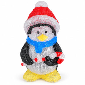A penguin-shaped decorative figure covered in textured, glittery material, wearing a red and white Santa hat, a bright blue scarf, black wings, a yellow beak and feet, and holding red-and-white striped candy canes, photographed on a plain white background.
