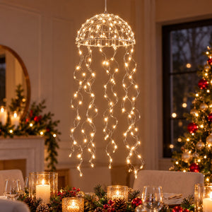 A hanging dome-shaped string light fixture with glowing warm white lights draped like tentacles over a decorated dining table in a festive indoor holiday setting.