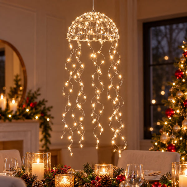 A hanging dome-shaped string light fixture with glowing warm white lights draped like tentacles over a decorated dining table in a festive indoor holiday setting.