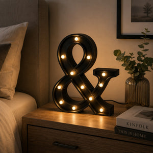Micasa LORA decorative LED ampersand table lamp on a modern bedside table creating a warm, cozy atmosphere.