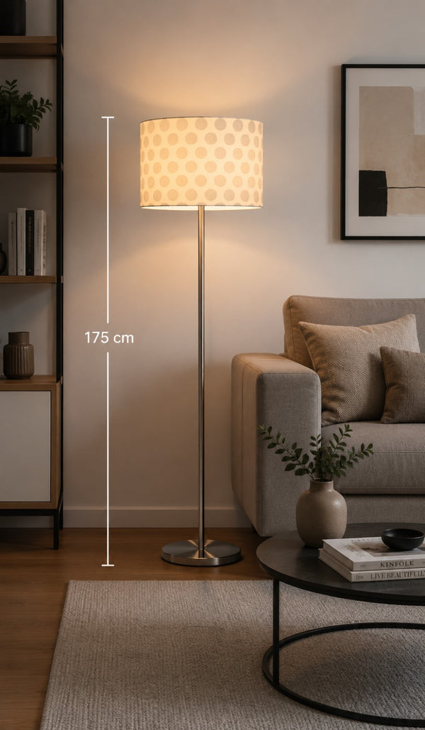 Micasa modern brushed nickel floor lamp with white fabric shade illuminating a contemporary living room beside a sofa, creating a warm and elegant atmosphere.