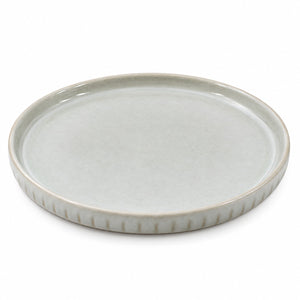 A round ceramic serving platter with a fluted rim, featuring a matte light gray-green glaze on a white background.
