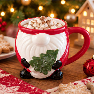 A festive ceramic mug shaped like a gnome, filled with a hot drink topped with marshmallows, set on a wooden table with Christmas decorations and blurred holiday lights in the background.