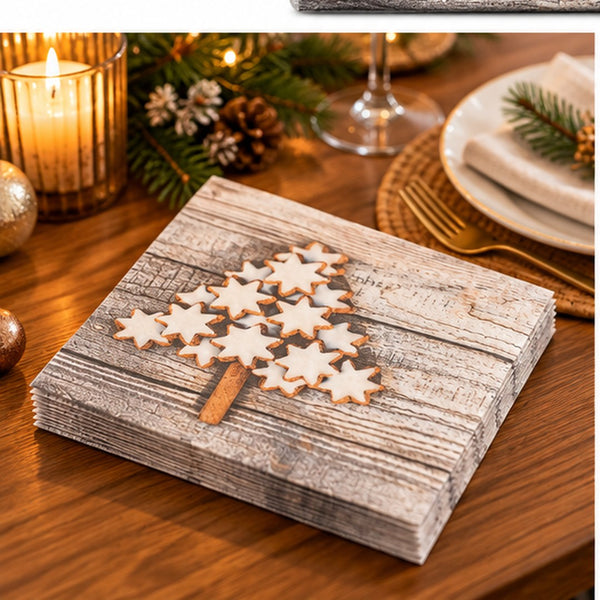 A stack of rectangular paper napkins with a rustic gray wood-grain print and a tree made of white star-shaped cookies with brown edges, set on a wooden table with holiday decor in the background.