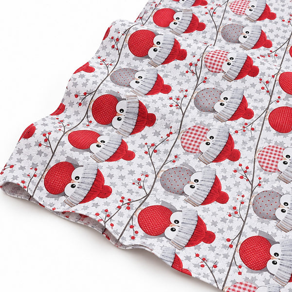 A folded piece of fabric with a festive owl pattern, featuring red and gray mittens, red-and-white checkered hats, and gray-and-white checkered hats on a light gray starry background.