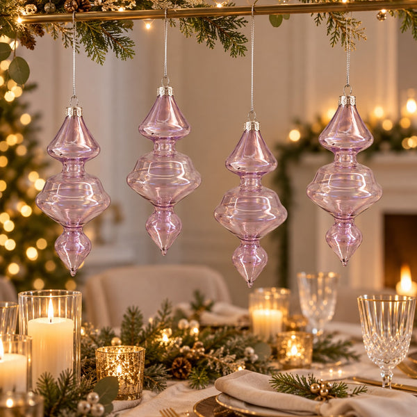 Four lavender purple ribbed glass Christmas tree ornaments hanging from a gold garland over a beautifully set dining table with candles and greenery.