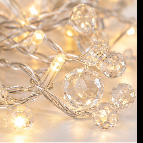 Warm white fairy string lights with faceted crystal ball bulbs and twisted wire, shown close up with glowing points of light.