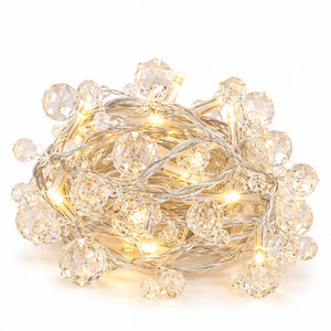Warm white crystal string lights with faceted clear beads and a silver wire, coiled on a white background.