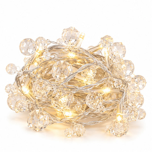 Warm white crystal string lights with faceted clear beads and a silver wire, coiled on a white background.