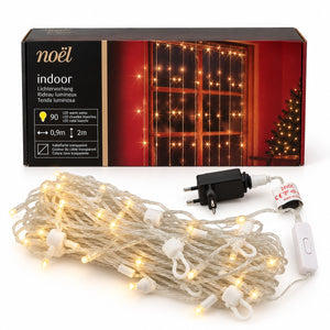 Noïel indoor Christmas curtain string lights with 120 warm white LED bulbs, shown coiled with its power adapter and switch, in front of its retail packaging box.