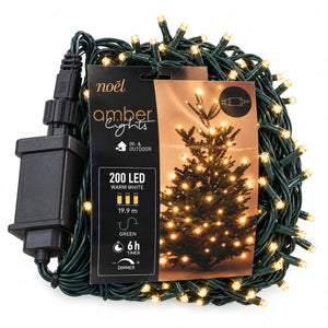 Coiled green outdoor LED string lights with warm white bulbs, shown with a black power adapter and a printed product card featuring a lit Christmas tree.