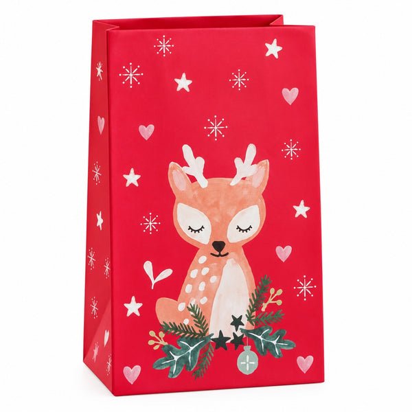 A red Christmas-themed gift bag featuring a cute cartoon deer illustration with antlers, surrounded by white stars, snowflakes, and hearts, and decorated with green pine branches and holly leaves at the bottom.