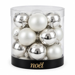 A set of silver and white Christmas tree ornaments inside a clear cylindrical container with a black base printed with the gold 'noël' brand name, on a white background.
