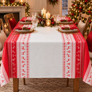 A festive Christmas table runner with red and white patterns, laid out on a dining table set for a holiday dinner in a decorated living room.