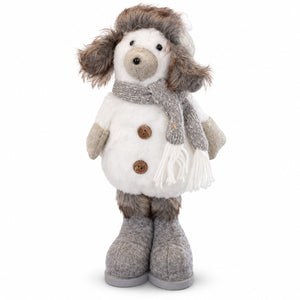 A plush dog doll dressed in winter clothing, featuring a white faux-fur coat with brown buttons, a gray knit scarf, gray knit mittens, and gray knit boots, set against a plain white background.
