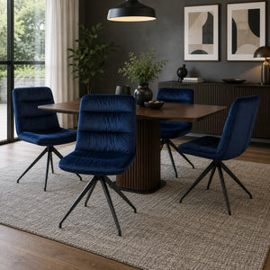 Scandinavian dining room furnished with navy velvet swivel dining chairs.