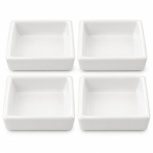 Four white square ceramic dishes arranged in a 2x2 grid on a plain white background.