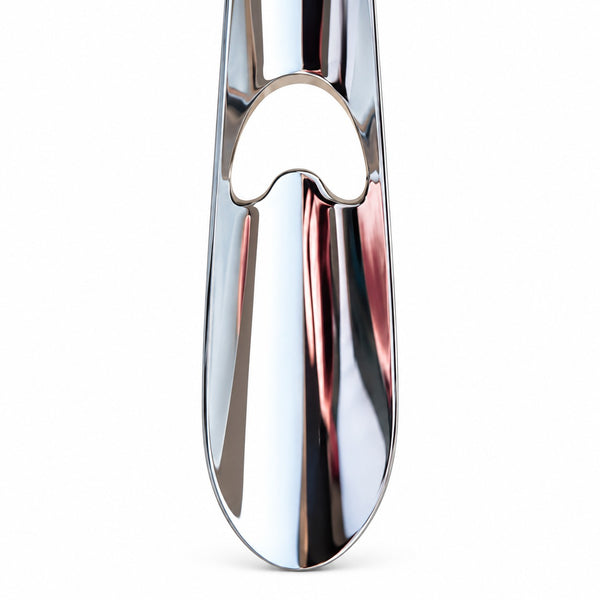 A close-up of a polished chrome metal object, likely a faucet handle or decorative hardware, featuring a reflective silver finish with a heart-shaped cutout detail, set against a plain white background.