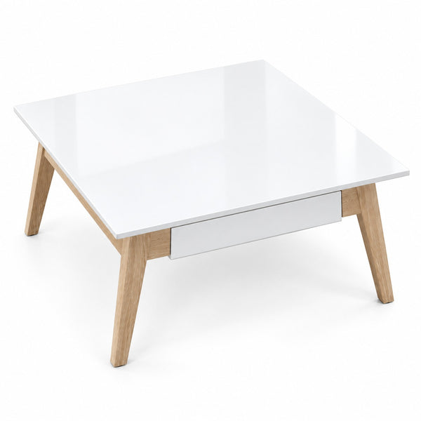 A modern square coffee table with a glossy white top and front drawer, supported by four light natural wood legs, shown on a white background.