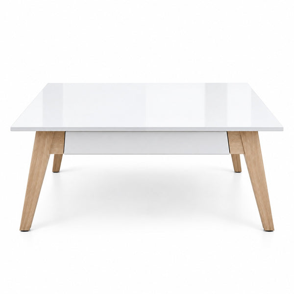 A modern square coffee table with a glossy white high-gloss top, a matching white drawer or center panel, and light natural wood legs, shown on a seamless white background.
